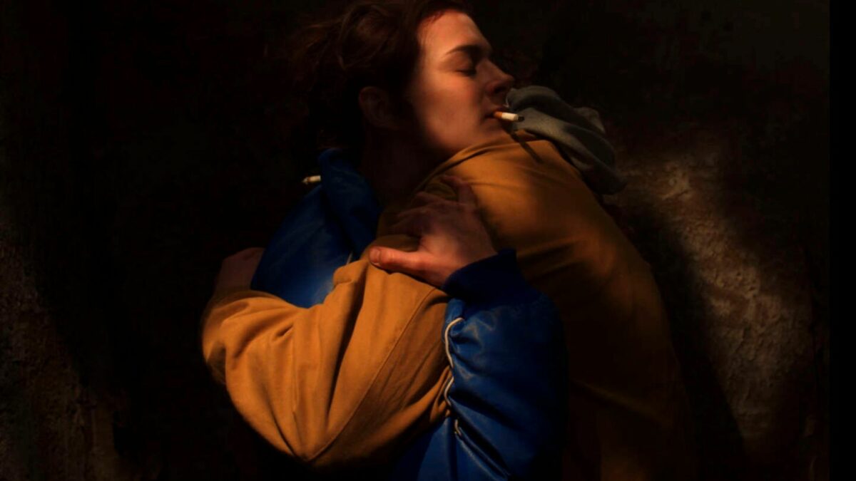 Kobieta z papierosem przytulająca się do innej osoby.