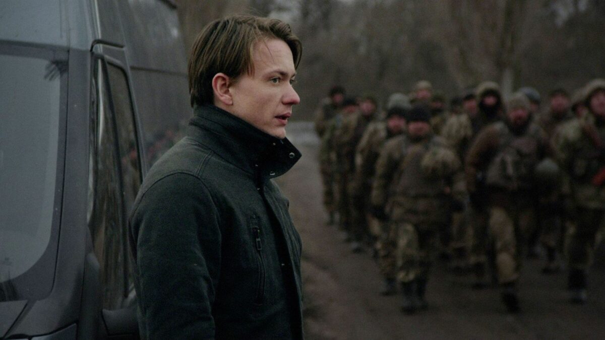 Mężczyzna stojący przed maszerującym wojskiem.