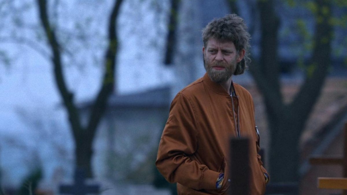 Młody chłopak na tle wiejskiego domu.