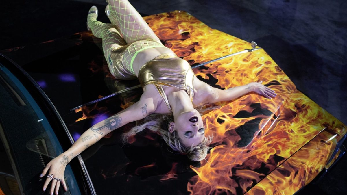 Kobieta w erotycznym tańcu na masce samochodu.