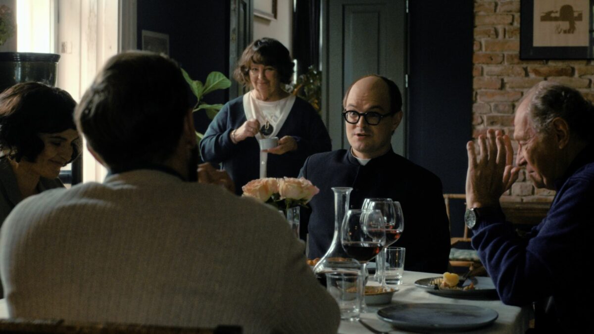 Scena przy stole, ksiądz w towarzystwie rodziny.