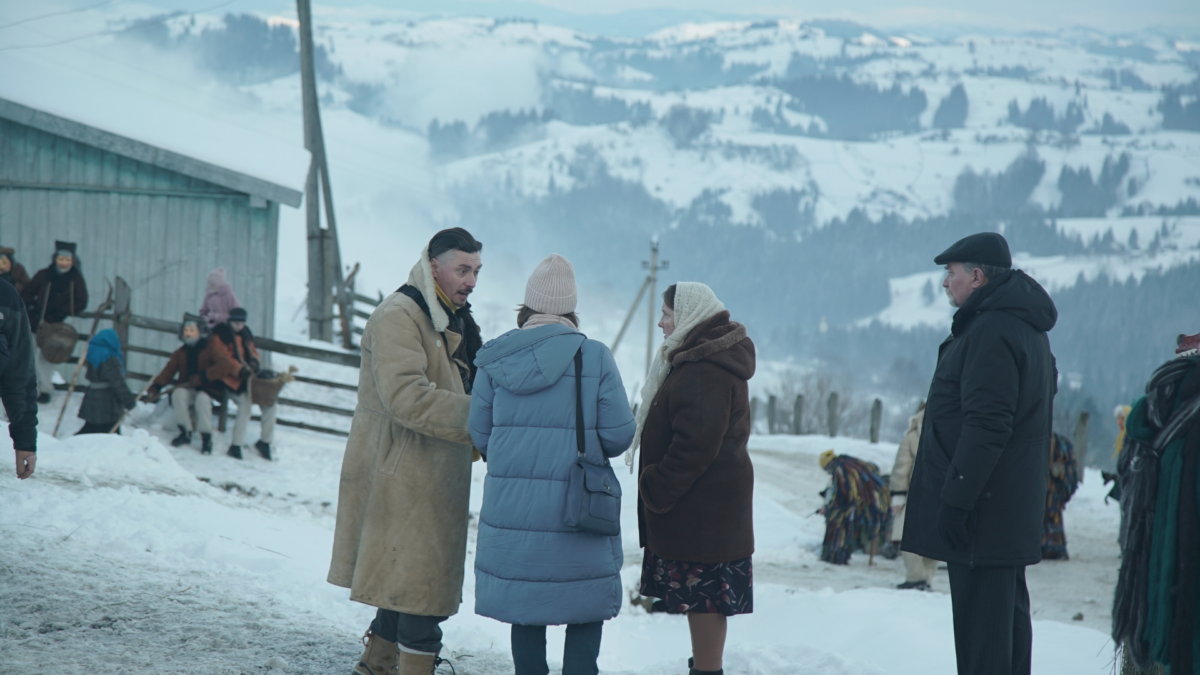 Mieszkańcy wioski zebrani na zewnątrz w zimowej scenerii.