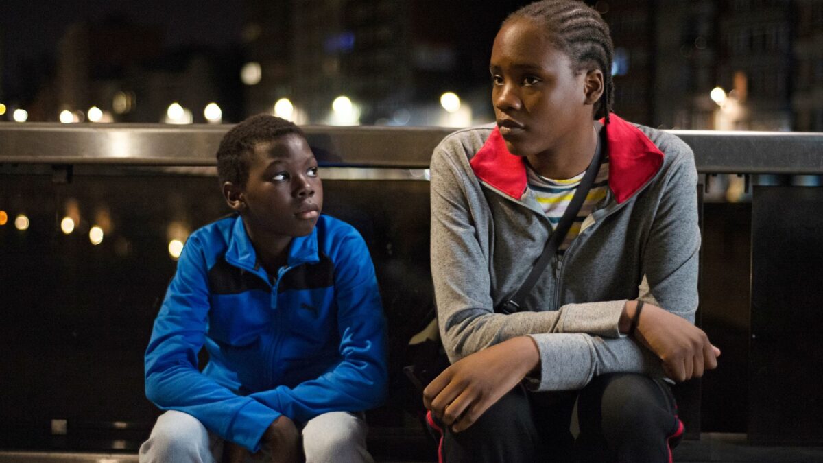 Nocny krajobraz miasta, na ławce siedzą dwoje nastolatków.