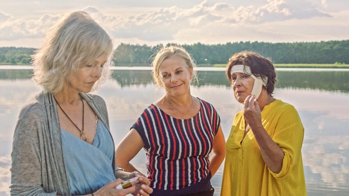 Kobieta z dwiema przyjaciółkami nad jeziorem.