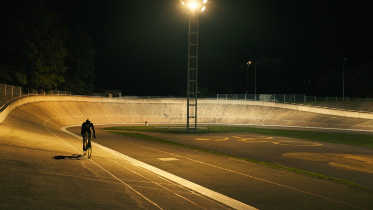 Mężczyzna jadący rowerem nocą po stadionie kolarzowym