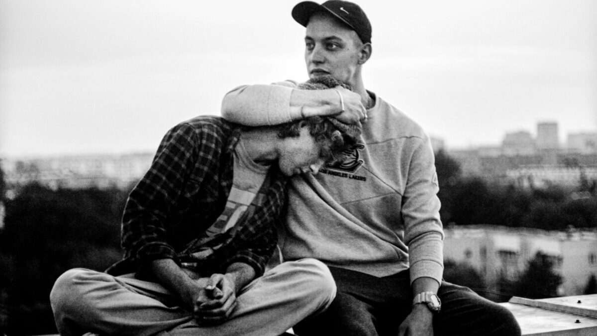 Starszy brat siedzi na murku ze swoim bratem.