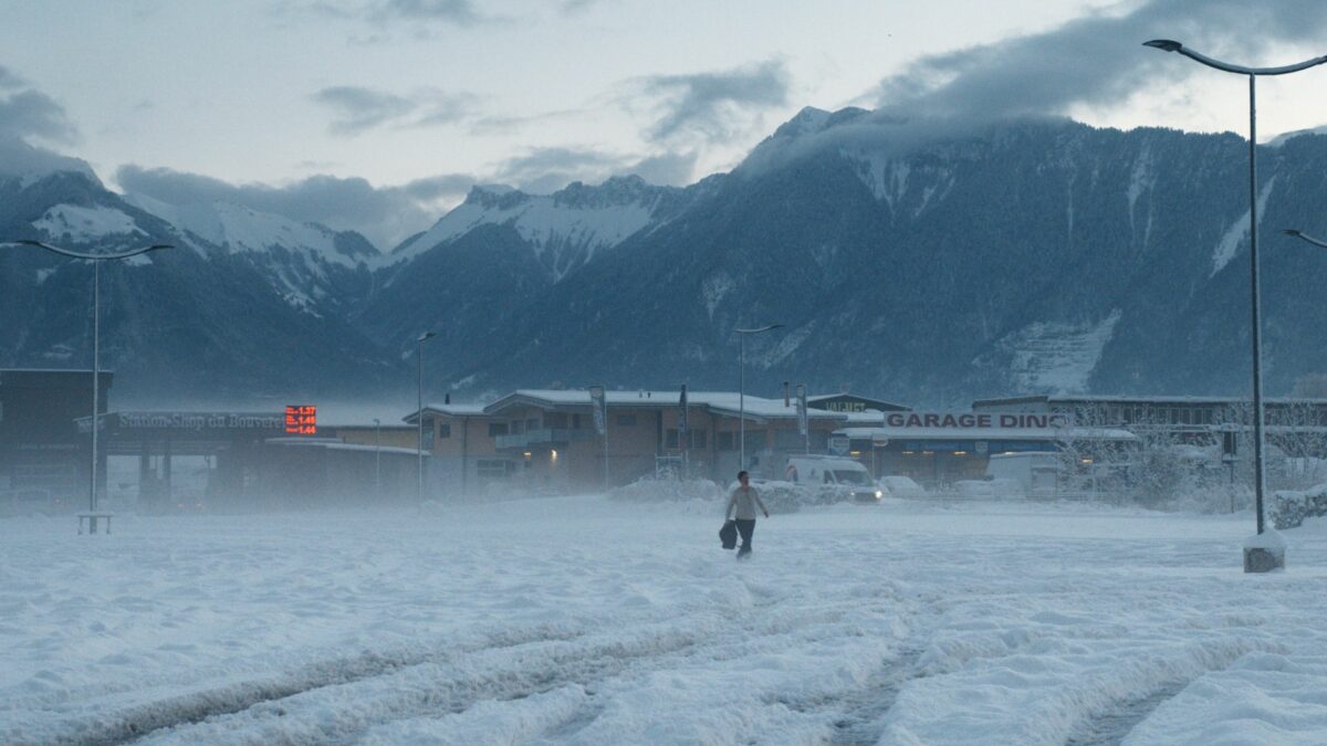 Pejzaże górskiego miasteczka, w oddali widać osobę idącą w śnieżycy.