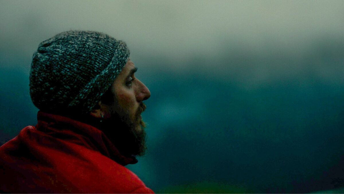 Zbliżenie na mężczyznę na tle rozmytego górskiego pejzażu.