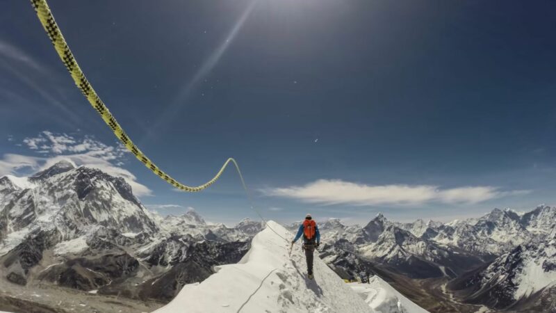 Ośnieżony szczyt górski, w oddali widać osobę zmierzającą na szczyt.