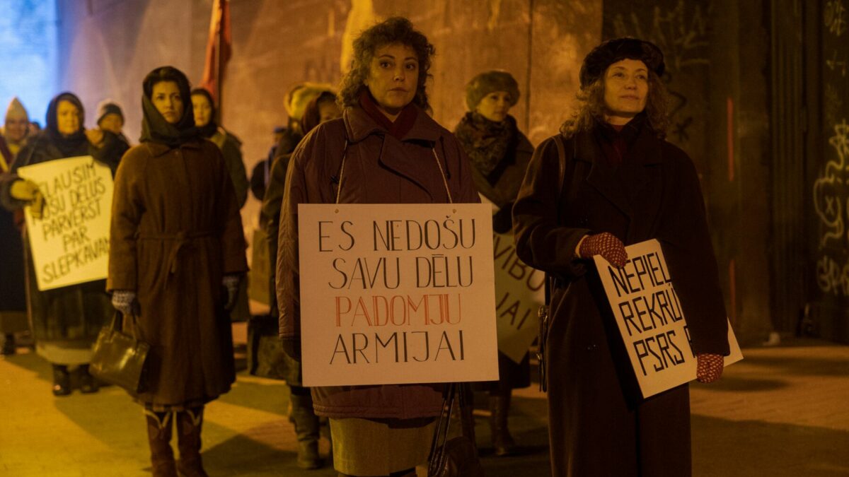 Grupa kobiet protestujących na ulicy z transparentami.