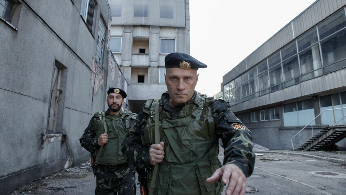 Dwóch żołnierzy na tle zniszczonego miasta.