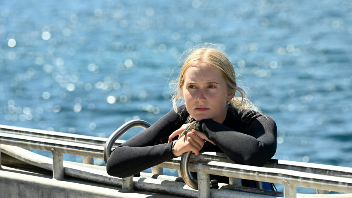 Młoda dziewczyna w stroju do nurkowania oparta o molo.