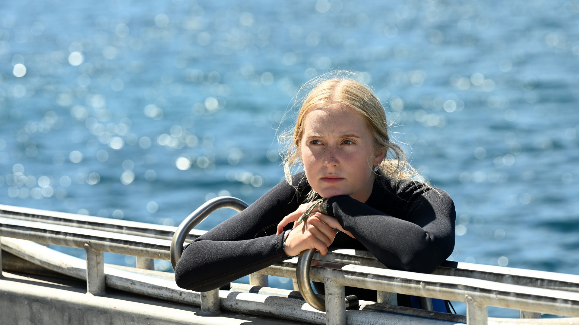 Młoda dziewczyna w stroju do nurkowania oparta o molo.