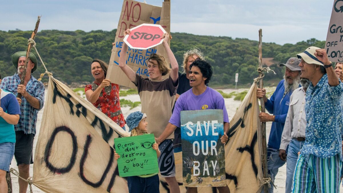 Grupa młodych ludzi protestująca na plaży.