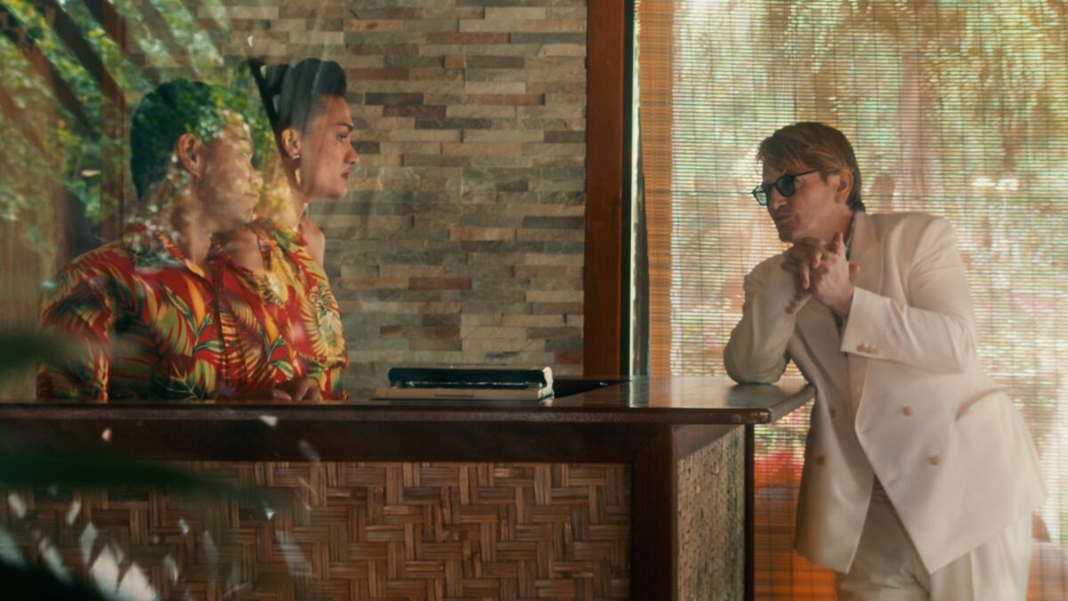 Scena z lobby hotelowego, za ladą dwójka pracowników na recepcji a przed nimi klient.