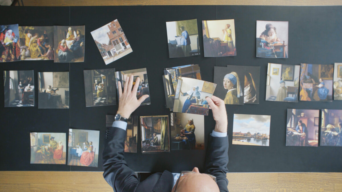 Kadr z góry na stół z fotografiami obrazów Vermeera.