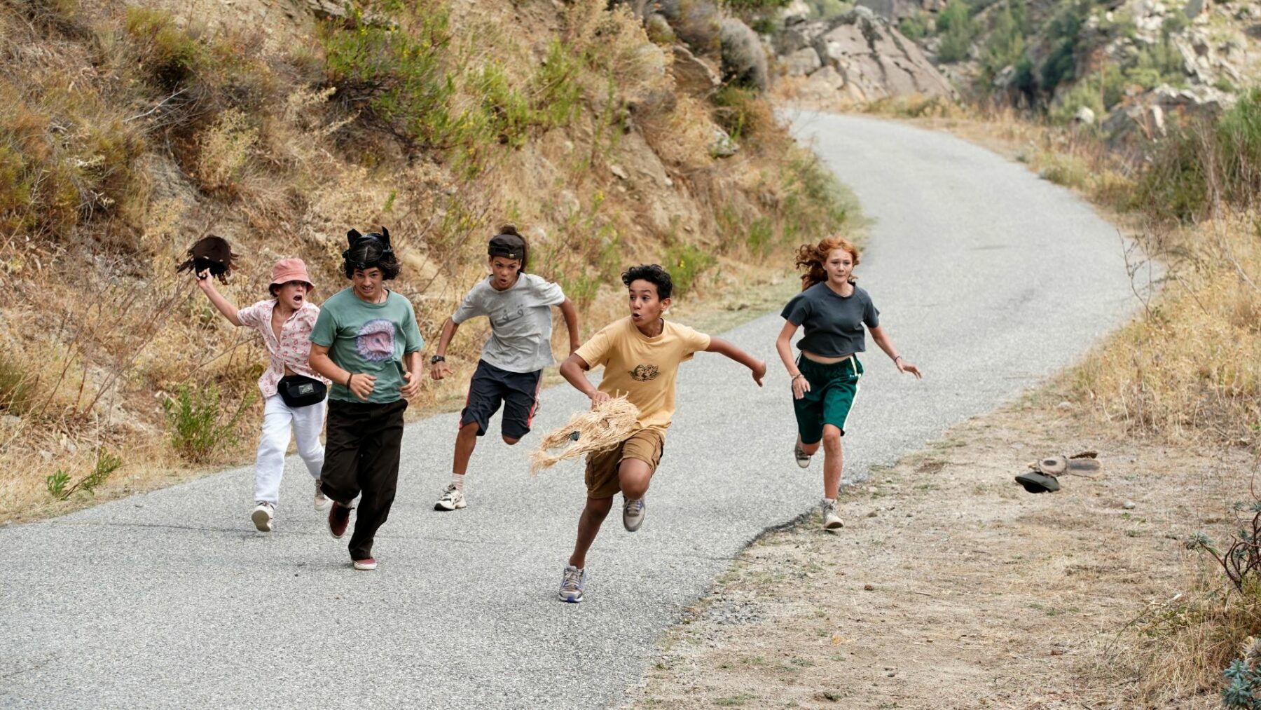 Grupa młodych przyjaciół podczas ucieczki, biegną po drodze.