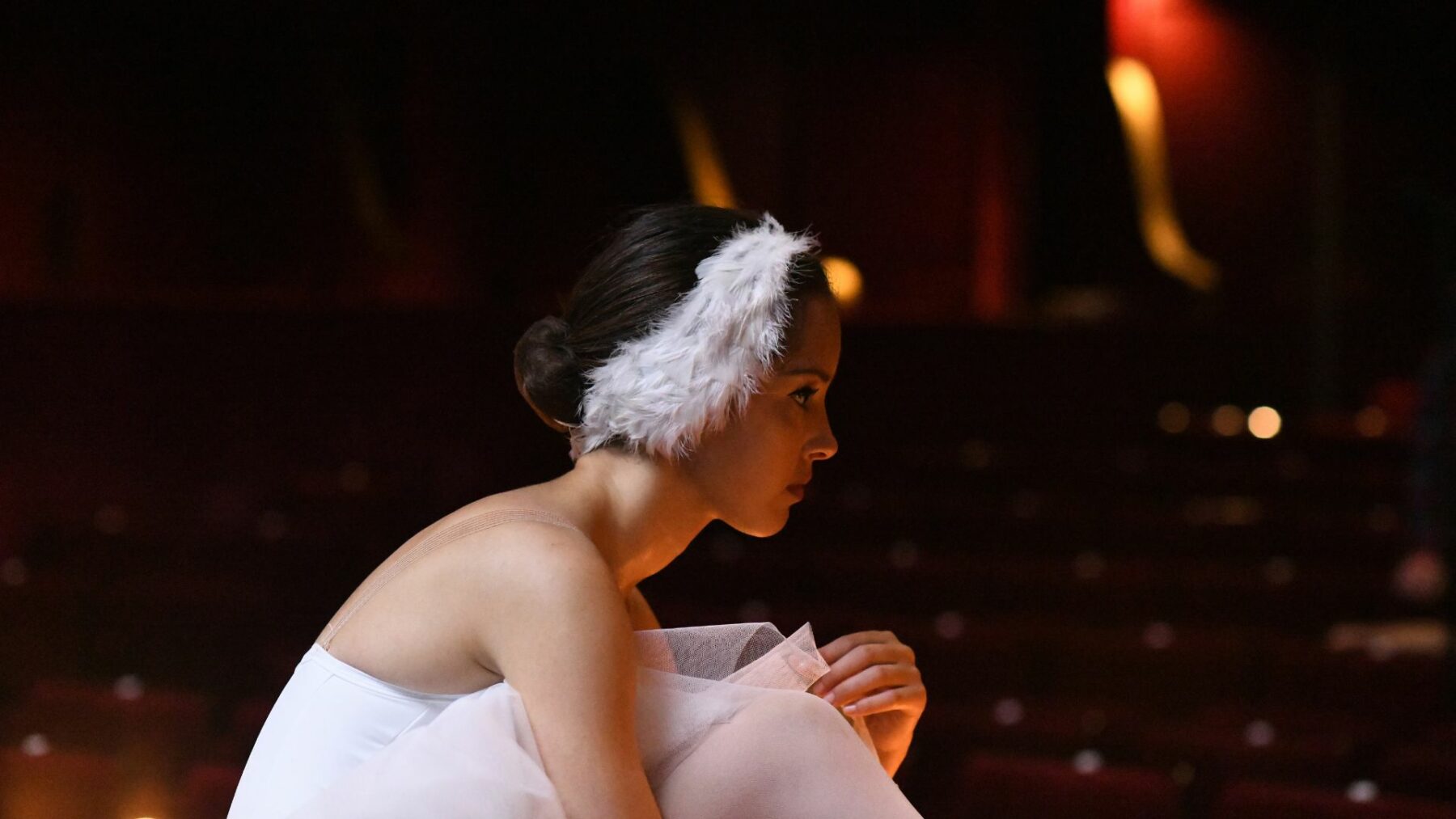 Tancerka w stroju baletowym na nieoświetlonej scenie.