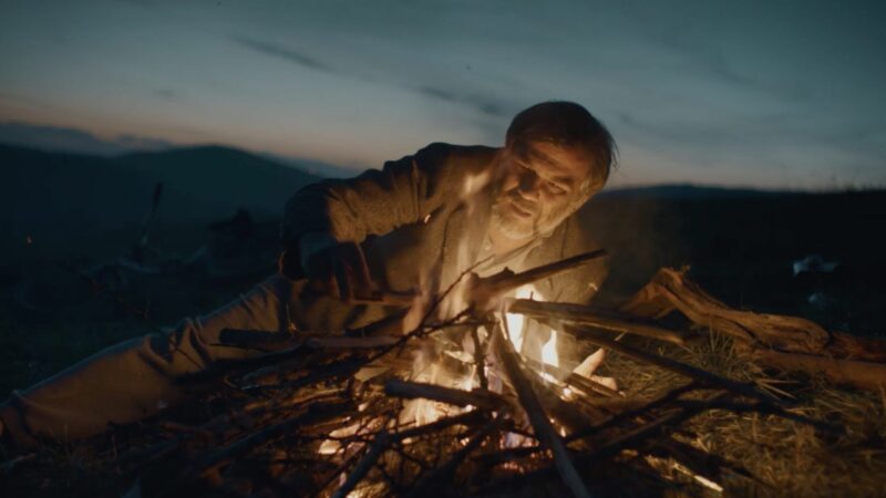 Starszy mężczyzna przy ognisku.