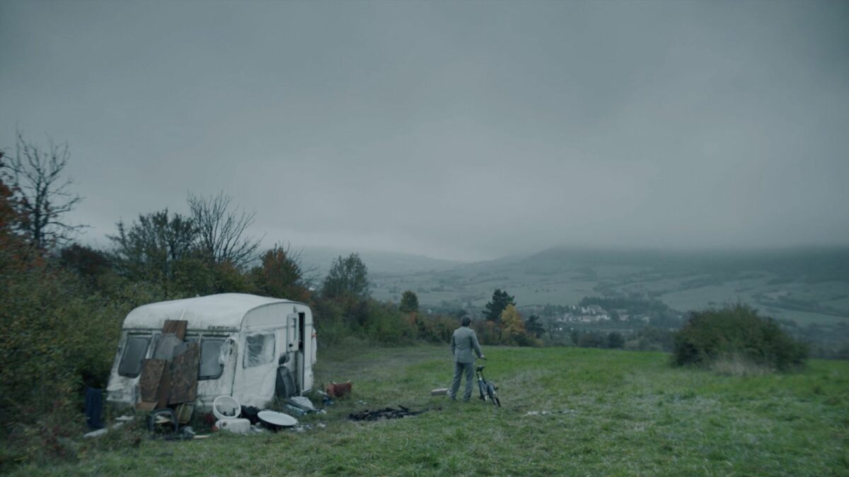 Krajobraz na rozległe łąki, w oddali widać kampera i mężczyznę na rowerze.