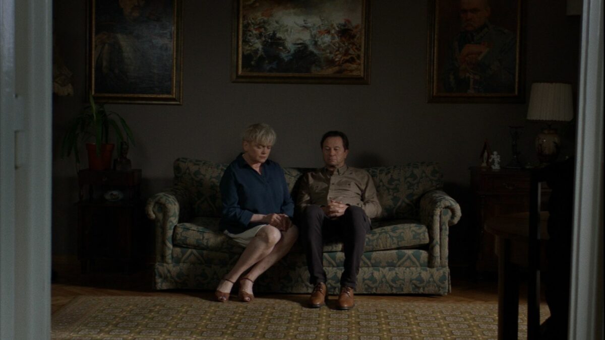 Kadr z salonu, małżeństwo siedzi na kanapie.