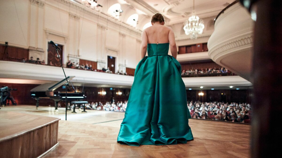 Widok na publiczność filharmonii, na głównym planie kobieta odwrócona tyłem.