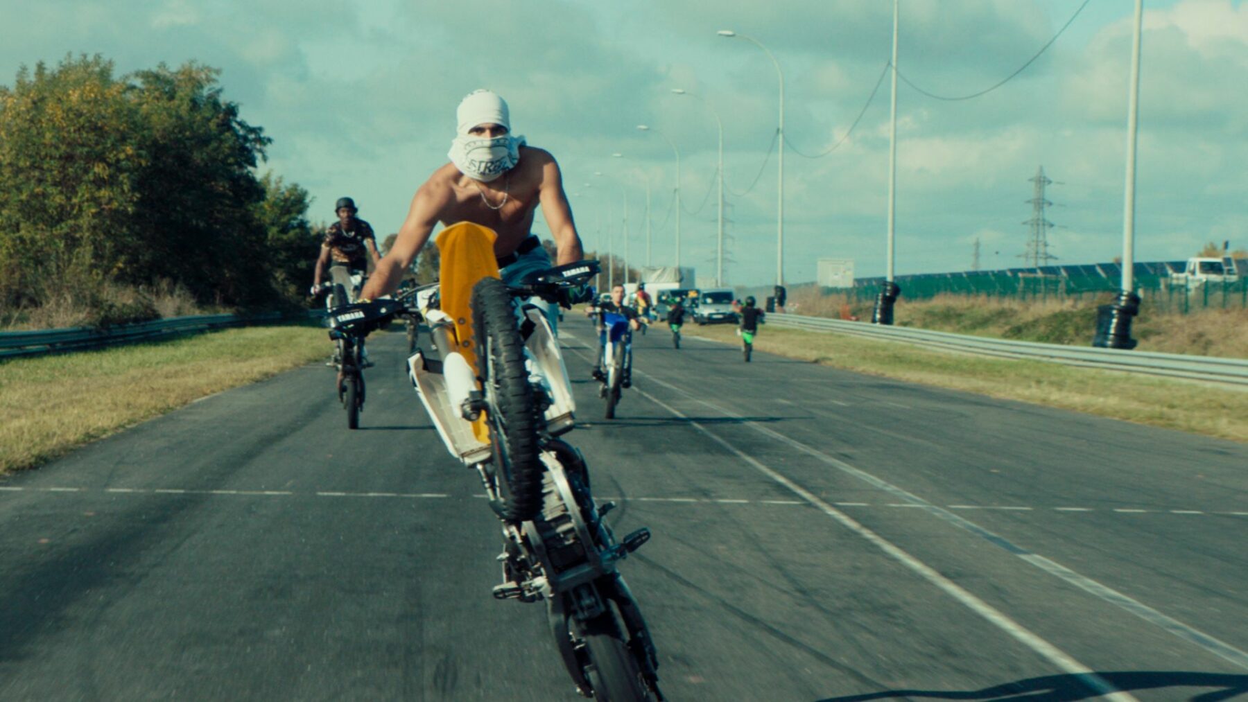 Kadr na autostradę a na niej rozpędzeni motocykliści.