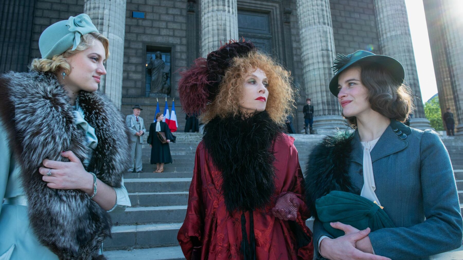 Trzy elegancko ubrane kobiety na schodach paryskiego sądu.