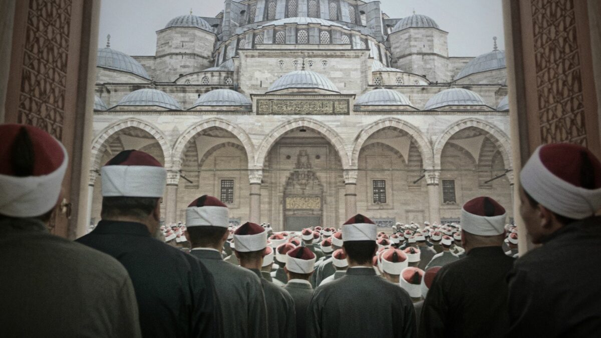 Kadr na grupę muzułmaninów stojących tyłem, zmierzają do świątyni.