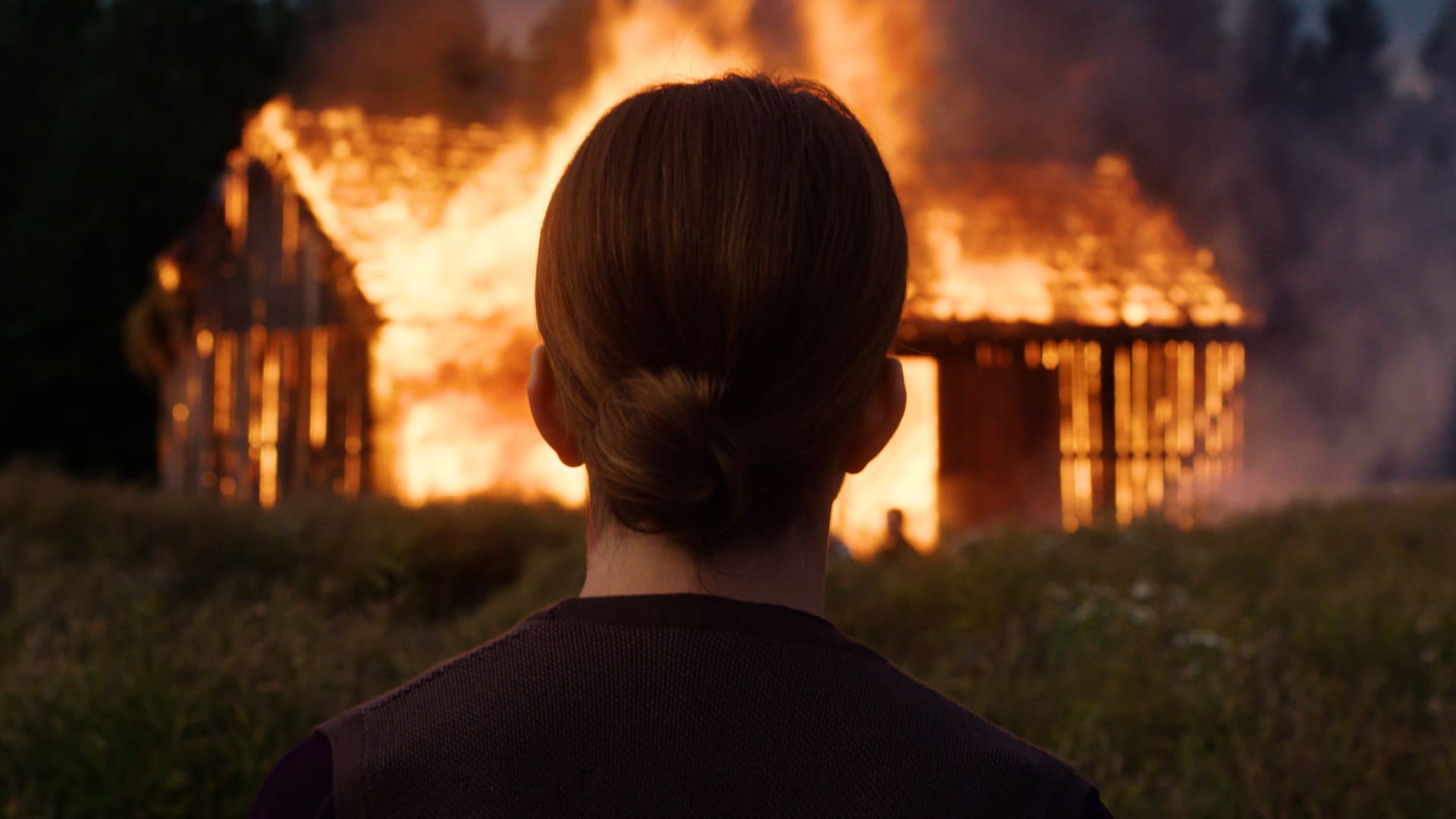 Płonąca chata i patrząca na to kobieta.