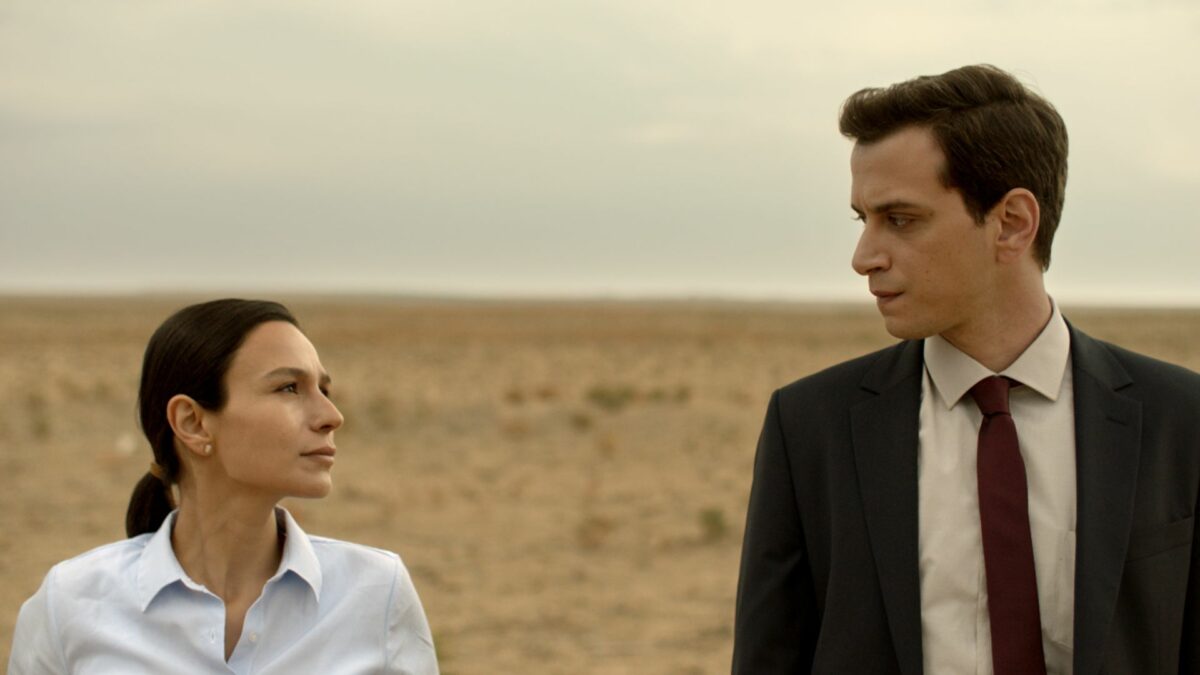 Mężczyzna w garniturze spogląda na kobietę, znajdują się na pustyni.