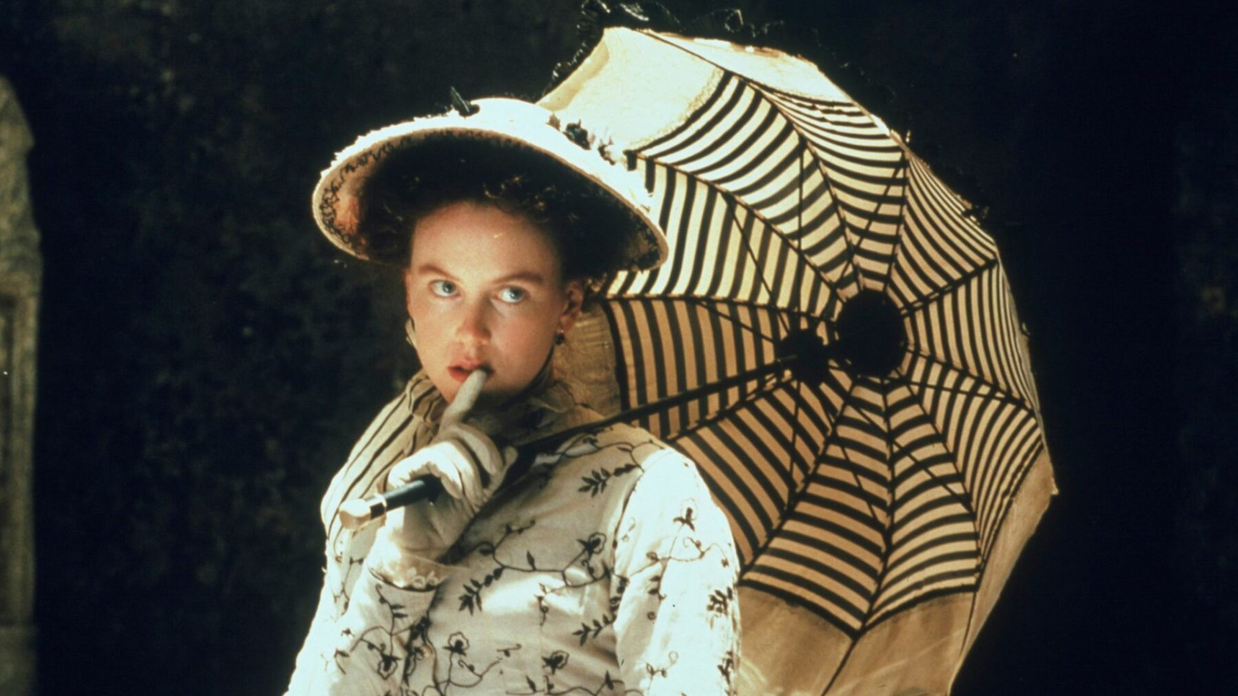 Kadr z kobietą w dziewiętnastowiecznej sukni, w dłoniach trzyma parasolką.