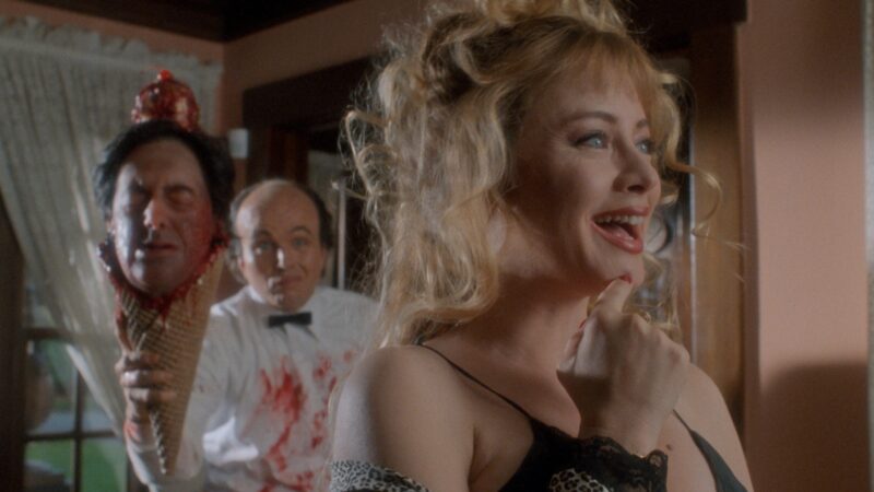 zadowolona kobieta a za nią lodziarz niosący rożek z ludzką głową.