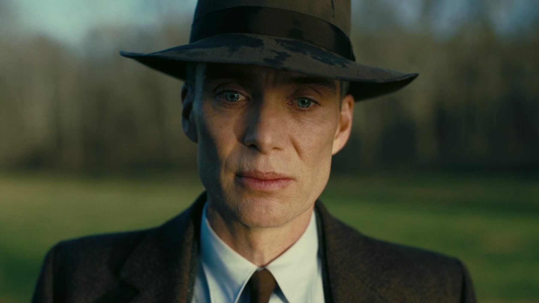 Zbliżenie na głównego aktora, mężczyzna jest w eleganckim garniturze i kapeluszu.