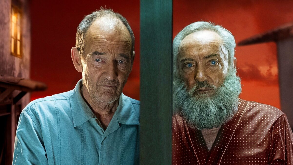 Dwóch mężczyzn ubranych w kolorowe piżamy patrzy z wyraźną niepewnością w oczach w obiektyw. Oddziela ich ściana, zadają się nasłuchiwać siebie na wzajem. Za nimi iskrzy się krwistoczerwone niebo