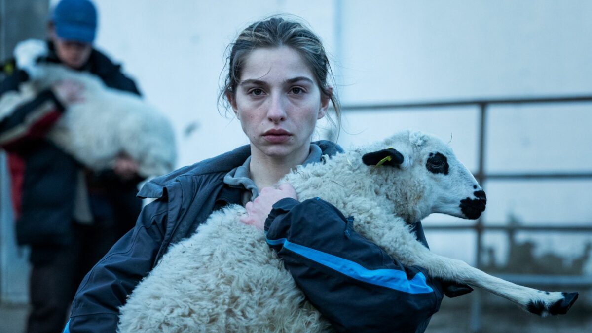 Dziewczyna z małą owieczką w rękach.