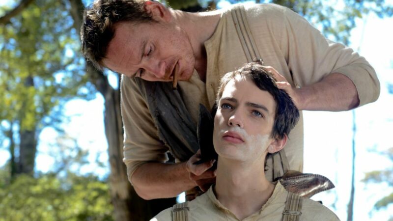 Mężczyzna goli swojego kompana brzytwą.