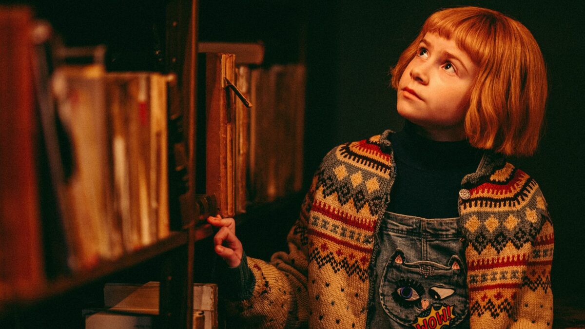 Dziewczynka przy regale z książkami.