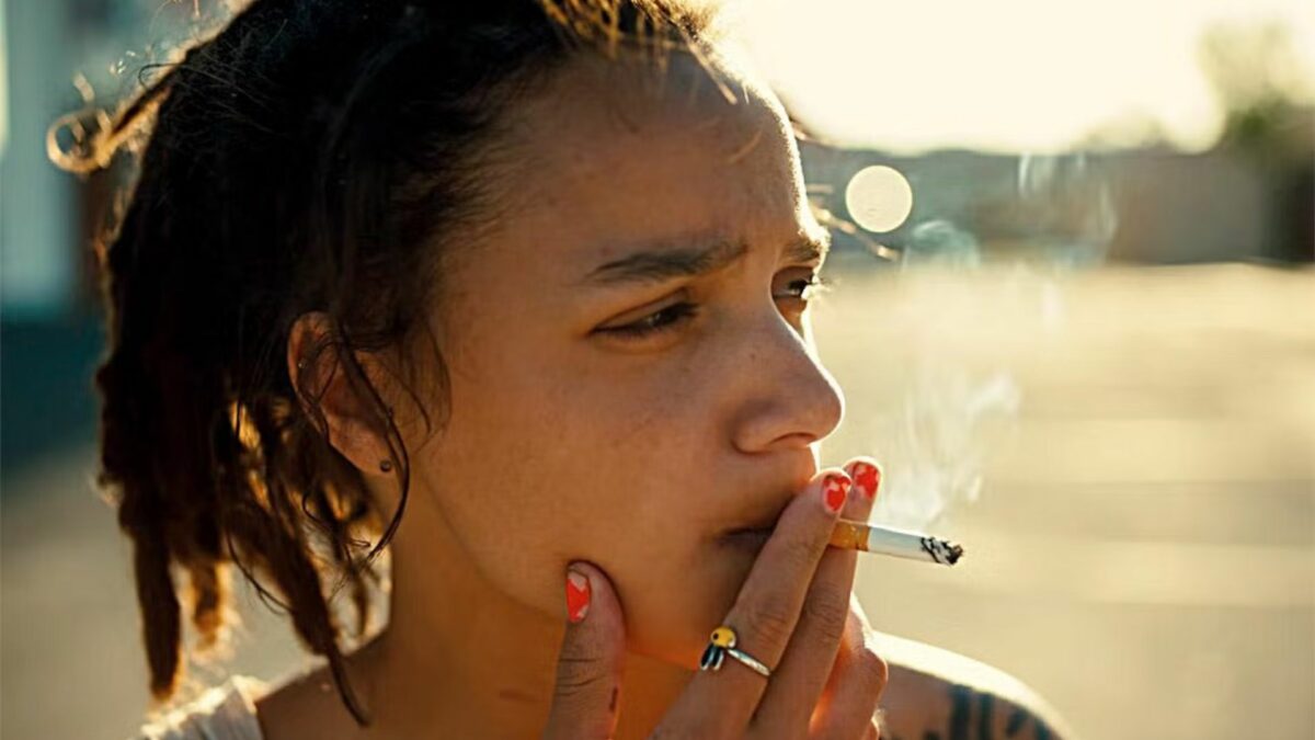 Zbliżenie na młodą dziewczynę palącą papierosa.