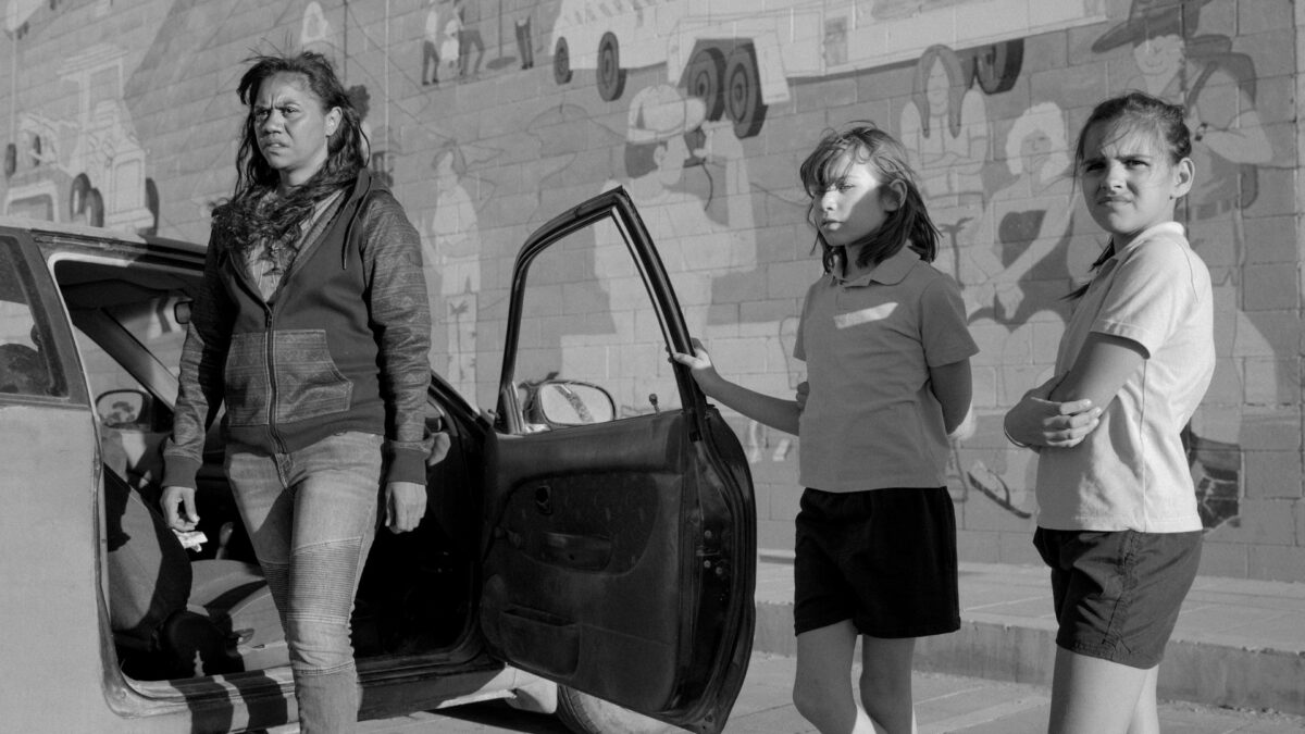 Kobieta wysiadająca z samochodu a obok niej dwójka dzieci.