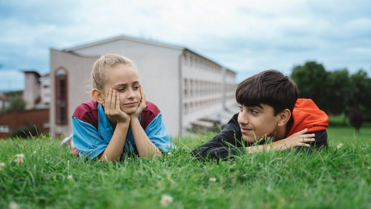 Dwójka młodych bohaterów odpoczywająca w letni dzień na trawie.