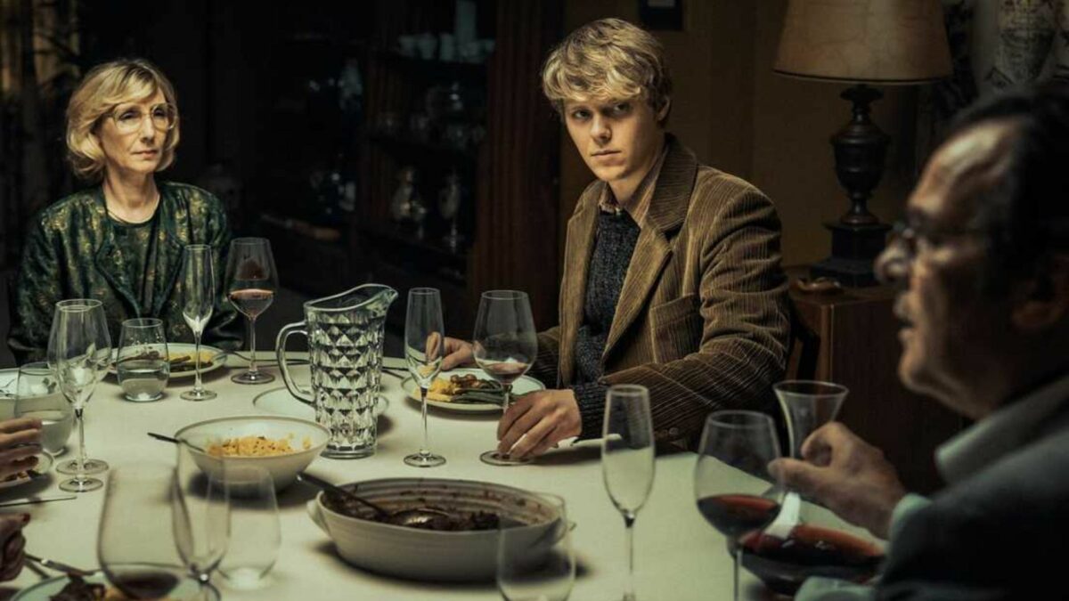 Młody chłopka z rodzicami przy zastawionym stole.