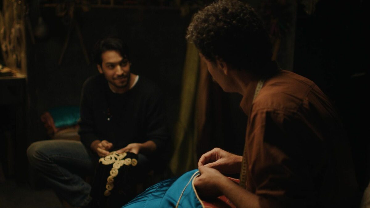 Dwójka mężczyzn przy szyciu sukni.