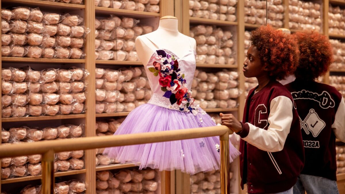 Młoda baletnica oglądająca na wystawie strój baletowy.