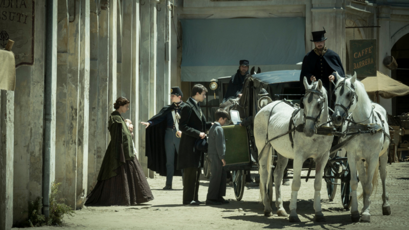 Widok na ulicę i dorożkę zaprzęgniętą w konie.