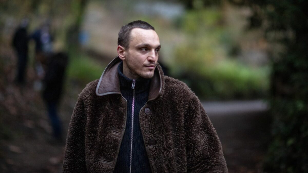 Młody mężczyzna ciepło ubrany w parku.