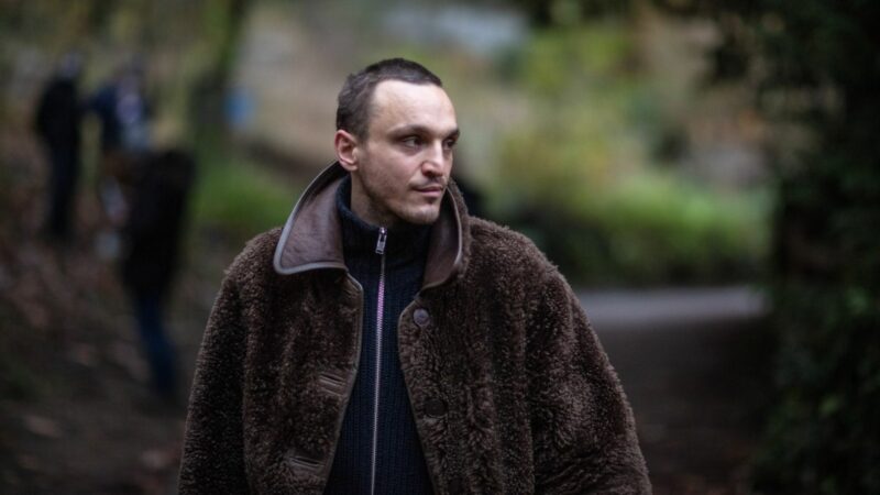 Młody mężczyzna ciepło ubrany w parku.