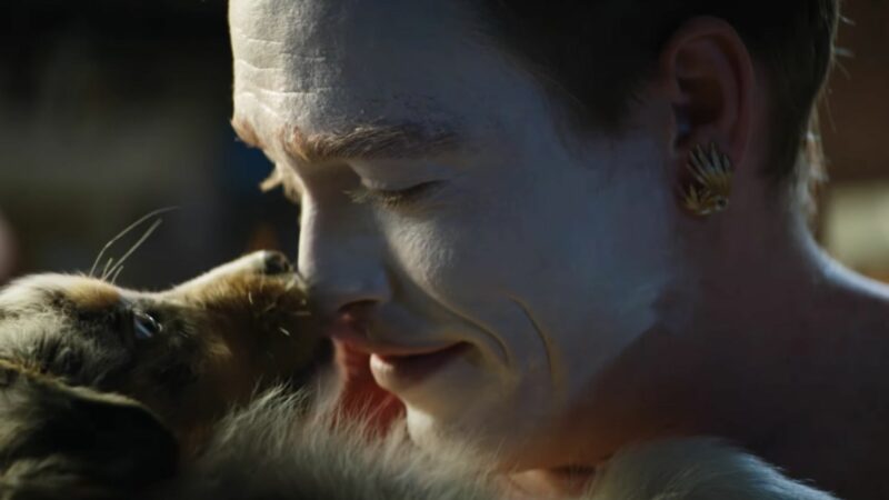 Mężczyzna z twarzą pomalowaną na biało w towarzystwie psa.