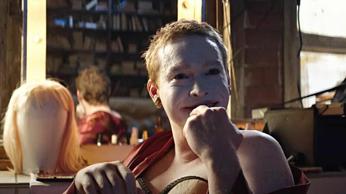 Mężczyzna w makijażu na tle garderoby.