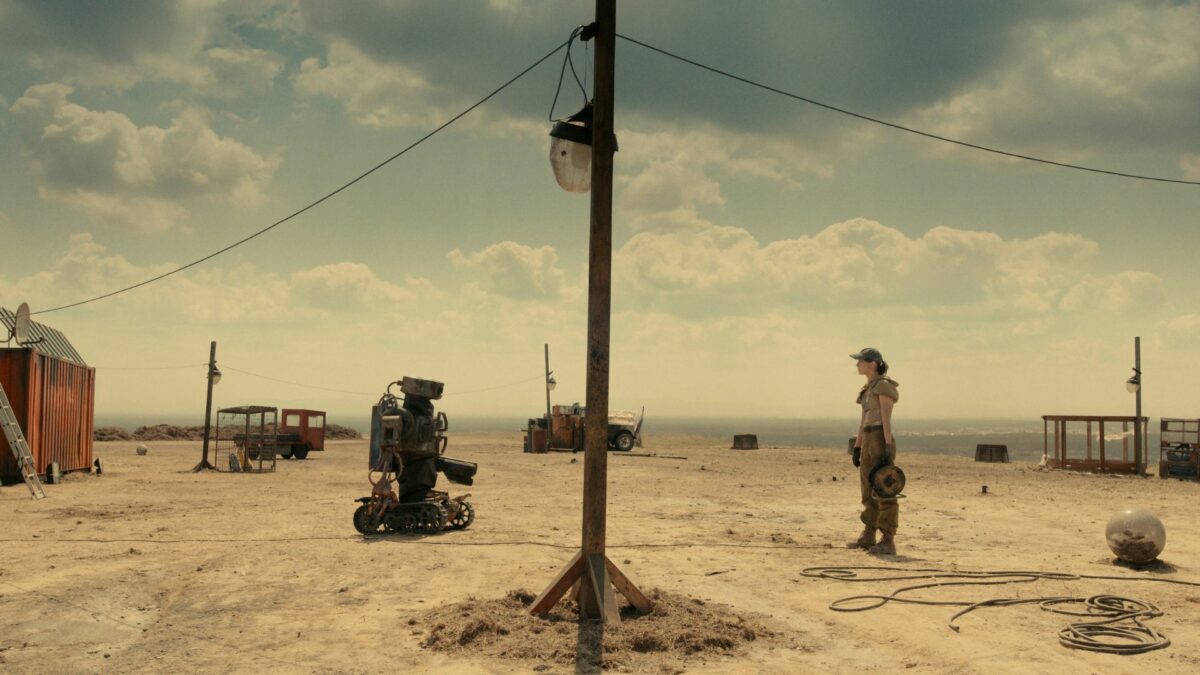 Pustynia a na niej stojący na przeciwko siebie robot i dziewczyna.